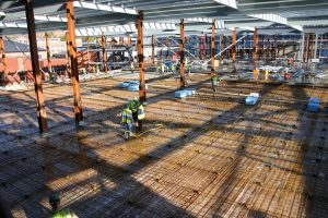 A group of engineers work on the exposed foundations of a bowling alley under construction